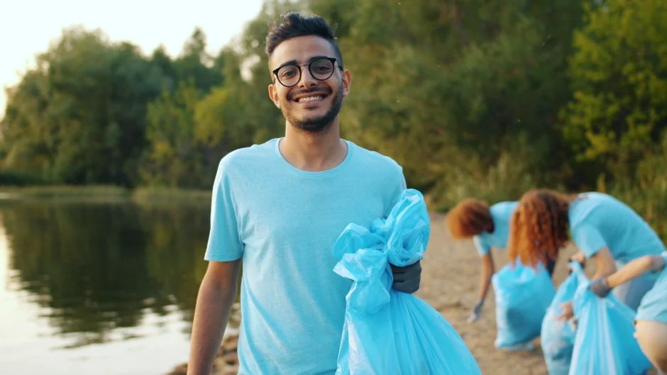 Close-up of hand cleaning window with squeegee outdoors using yellow gloves.